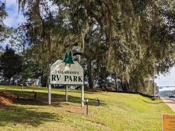 Park entrance sign standing under hanging Spanish moss