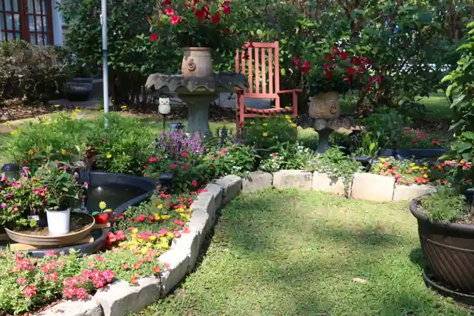 Curving stone-edged garden bed with a fountain and a red rocking chair