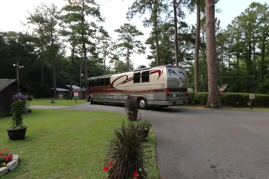 Class A motorhome parked on a landscaped site beside a planter of red flowers