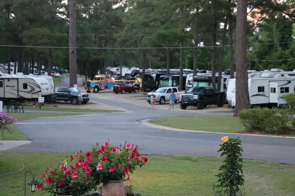 Park loop road edged with flowers, RVs and tall pines